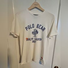 Polo Bear Graphic Tee. Super Soft Cotton, Ivory Body With “Ranch Bear” Graphic On Front, “Hand Written” Script And Embroidered Embellishments On Front And Back. Custom-Fit Medium. Nwot. Never Been Worn. White Cotton Shirt With Embroidered Logo, White Casual Shirt With Embroidered Logo, Classic Cotton Top With Embroidered Graphics, Casual White Tops With Embroidered Logo, White Cotton Shirt With Embroidered Graphics, Classic Embroidered Short Sleeve Top, White Crew Neck Shirt With Embroidered Logo, White Embroidered Graphic Tee, Classic Embroidered Cream Top