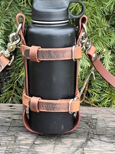 a black water bottle with leather straps on a wooden table