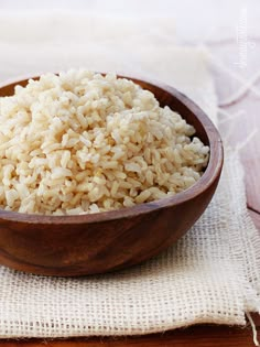 a wooden bowl filled with rice on top of a table