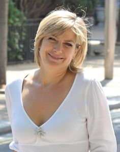 a woman in a white dress is smiling at the camera with her hand on her hip