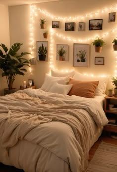 a bed with white sheets and lights on the wall above it, surrounded by potted plants