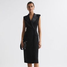 The Black Amari Dress Nods Toward Traditional Menswear Tailoring With Its Confident Double-Breasted Shape, Padded Shoulders, And Four-Button Fastening. It S Given A Feminine Twist With Satin Lapels And A Chic Midi Length, Which Wraps Close Against The Frame. Style Tonally For A Timeless Look. Wrap Design. Double Breasted. Satin Peak Lapels. Padded Shoulders. Sleeveless. Four-Button Fastening. Flap Pockets. Midi Length. Fitted. Lined. The Model Is Wearing A Size 8. Measurements Of Model: Height 5ft 10'' / 178cm. Regular Side Neck To Hem 45.5" / 115cm. Tailored Black V-neck Dress, Tailored Structured Black Dress, Luxury Black Structured Dress, Luxury Sleeveless Formal Dresses, Fitted Black Business Dress, Fitted Structured Dress For Semi-formal Occasions, Silk Midi Dress For Evening Formal Events, Black Fitted Dress For Business, Tailored Structured Midi Dress For Formal Occasions