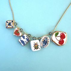 a necklace with four different designs on it, including cherries and ladybugs