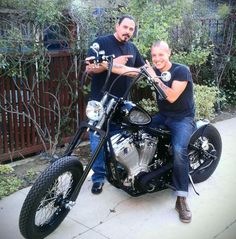 two men sitting on a motorcycle posing for the camera