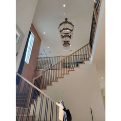 a chandelier hanging from the ceiling in a room with white walls and stairs