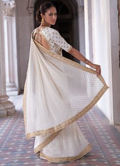 This look features an ivory Benarasi saree set. The flowy georgette has woven gold motifs with handcrafted zardozi and pearl border. A matching embellished closed neck blouse with back keyhole completes the look. Composition: Blouse - Viscose georgette, Saree - Viscose georgette, Underskirt - Satin Care: Dry Clean Only and Vacuum Storage This product can be customised for colour, sleeves, length of blouse and neck design Delivery : 2 weeks as the product is hand crafted. For more information and sizes please contact fabiliciousfashion@gmail.com or visit our Copenhagen studio.About the Designer : Renee Label was created in 2013,by the talented sister duo Pooja and Karuna, is a culmination of their love for fashion and art. The mesmerizing wedding wear collection that tells enchanting storie Ivory Saree, Pearl Border, Dori Embroidery, Net Blouse, Mirror Work Blouse, Add Sleeves, Vacuum Storage, Indian Wedding Wear, Georgette Blouse