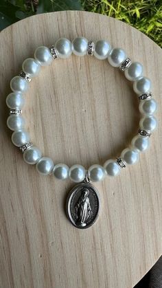 Beautiful Bracelet made with 8mm White Glass Pearls, and 6mm  silver Rhinestones beads  and the Miraculous Medal charms and the crucifix. The measurement of the medal is 1" or 2 cm and the cross is 2" or 5 cm. . The total measurement of the bracelet is 7" or 17.8 cm. The weight of the bracelet is 17 grams. Beautiful instrument of prayer or to give as a gift on any special occasion. Wearing a bracelet with the Miraculous Medal on your wedding day is a gesture full of meaning and devotion. This sy Silver Pearl Stretch Bracelet For Gift, Silver Pearl Stretch Bracelet As Gift, Silver Pearl Stretch Bracelet Gift, Silver Adjustable Rosary Bracelet For Wedding, Handmade Silver Rosary Bracelet For Wedding, Adjustable Beaded Rosary Bracelet For Wedding, Handmade Adjustable Rosary Bracelet For Weddings, Handmade Rosary Bracelet With Round Beads For Wedding, Silver Hand-strung Bracelet For Wedding