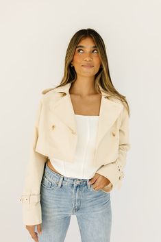 this cropped trench coat-esque jacket will take any spring outfit to the next level. it features chic tortoise shell buttons + has the most perfect cropped silhouette. whether you throw it on to elevate a basic outfit or use it as the focal point of your ensemble, it’s guaranteed to get you allll the compliments. butter // lapel collar, buttons, cuffed sleeves paired with our lotti tank + sicily distressed denim model is 5'7" + wearing a small measurements are approximate + taken while laying fl Beige Cropped Jacket With Button Closure, Chic Cropped Outerwear For Spring, Workwear Cropped Jacket With Double Button, Cropped Workwear Jacket With Double Button Closure, Cropped Jacket With Double Button Closure For Work, Beige Cropped Crop Top For Fall, Fall Beige Cropped Crop Top, Beige Cropped Top For Fall, Chic Button-up Crop Top For Spring