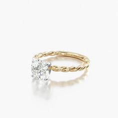 a yellow gold engagement ring with a single diamond in the center, on a white background