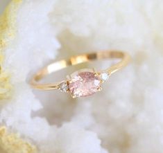 a pink diamond ring sitting on top of a white piece of paper