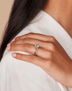 a woman's hand wearing a gold ring with a diamond on the middle and side