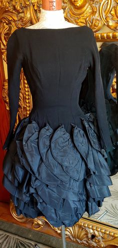 "This is an amazing dress! Very high quality. The top of the dress is made of soft black wool. Princess seaming for a tight fit. At the top of hip starts rows and rows of ruffled black taffeta. This is attached to very heavy interfacing. It is a pencil fit underneath. There is only one area on one of the ruffles that has some marks three very tiny holes. I believe the marks will lighten up or possible dissapear with some care. I am going to try to work on it. Right now it is sold as is. Aside fr Cocktail Taffeta Dress With Voluminous Skirt, A-line Taffeta Dress With Ruffles, Black Voluminous Dress With Ruffled Skirt, Steampunk Black Dress With Ruffles, Black Vintage Ruffled Skirt, Black Sequin Gown, Square Dance Dresses, Classy Prom, Classy Prom Dresses