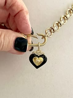 This shiny gold-plated cable chain necklace has a great weight to it. It connects to a gold rope design spring lock carabiner. The pendant is made of black enamel, pave stones, and a double heart in gold. The bale on the pendant is also encrusted in pave. This is a show-stopping necklace of modern and trendy design. The chain is lead-safe and nickel free. The chain's large link is 1/2 in and the middle link is 1/4 in. The Carabiner and chain is brass with 14k gold plating. The length of the neck Gold Charms For Necklace, Chunky Charm Necklace, Black And Gold Necklace, Carabiner Necklace, Cable Chain Necklace, Necklace Clasps, Heart Pendant Gold, Bag Belt, Chunky Jewelry