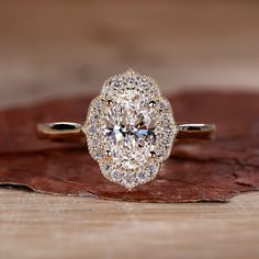 a diamond ring sitting on top of a wooden table next to a brown and white leaf