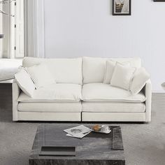 a living room with white couches and pictures on the wall above them, along with a coffee table