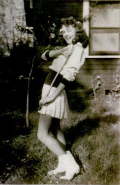 an old black and white photo of a woman holding a violin in front of a house