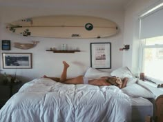 a woman laying on top of a bed next to a surfboard above her head