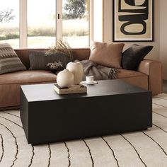 a living room with a couch, coffee table and rugs on the floor in front of large windows