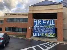 a car parked in front of a building with a for sale sign on it