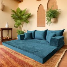 a large blue couch sitting on top of a rug next to a potted plant