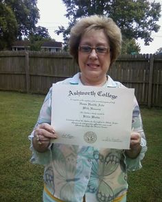 an older woman holding up a certificate in her hands