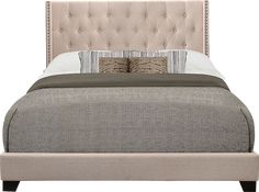 an upholstered bed with two pillows on the headboard and one foot board