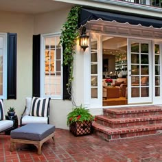 a patio with two chairs and a couch on it next to the stairs leading up to an open door