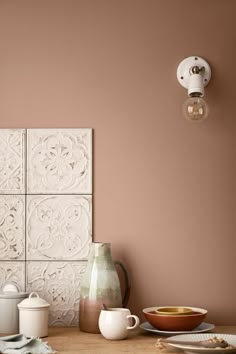 a kitchen counter with dishes and utensils on it next to a wall light