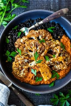 a bowl filled with black beans, carrots and meat on top of it next to a spoon