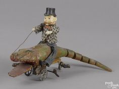 an old toy with a man riding on top of a small dinosaur that is attached to a cart