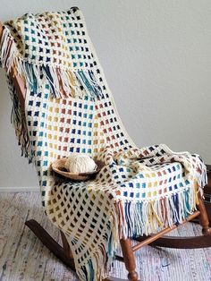 a rocking chair with a blanket on top of it next to a wall and floor