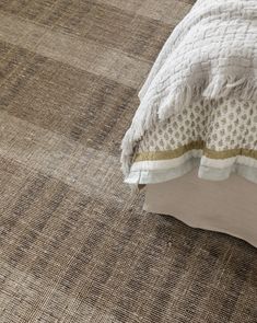 a bed with a white comforter on top of it next to a brown rug