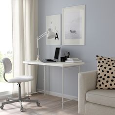 a white desk with a laptop computer on top of it next to a chair in front of a window