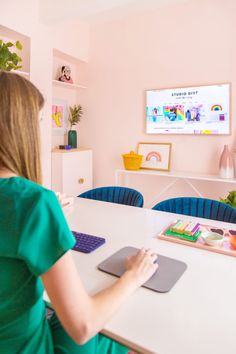 a woman sitting at a table with a mouse and keyboard in front of a flat screen tv