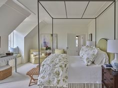 a bedroom with four poster bed, white walls and carpeted flooring is shown