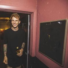 a man standing in front of a doorway holding a beer