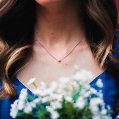 a woman wearing a blue dress holding a bouquet of white flowers and a diamond necklace