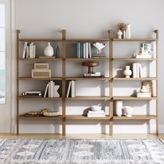 a bookshelf filled with lots of books on top of a wooden floor next to a window