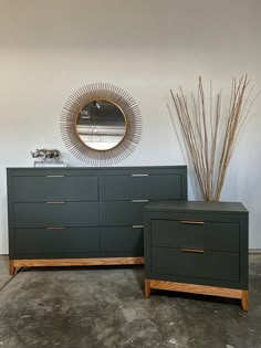 two green dressers sitting next to each other in front of a round mirror on the wall