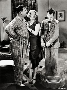 three people are standing in front of a water fountain and talking to each other while the man is wearing a suit