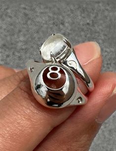 🎱 MAGIC 8 BALL SIGNET RING - Sterling Silver 🎱   Made-to-order in 2-3 weeks (but worth the wait!)  High-polish glossy finish, The Magic 8 Ball Signet ring is an original Honey Drip Jewelry design. The signet ring has a 3D construction featuring a cut-out 8 with a hollowed inside. The band of this piece is designed to be sturdy so it's a piece you will love and have forever. Features signature embossed Yin Yang halves on the signet's shoulders. * Magic 8 Ball Signet ring * Sterling Silver * 12mm measurement across signet face * Made in NYC * MADE-TO-ORDER IN 2-3 WEEKS Each step of production is done in NYC with care. Please allow for small variations in each piece as they are produced by hand with natural materials! Shop the matching 8Ball Charm by HONEY DRIP NYC Jewelry on our Etsy Shop. Drip Jewelry, Crystal Ball Ring, Magic 8 Ball, Original Jewelry Design, Nyc Jewelry, Signet Rings, Gold Ring Designs, Linking Rings, Fortune Teller