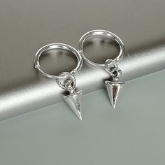 A PAIR of sterling silver hoops. Comes with a detachable spike charm. The charm is multipurpose and can be used with a neck or bracelet chain too. Dimension: Hoop- 1.2 x 12 mm Spike charm: 5 x 9 mm Weight: 1.6 gm Price is for ONE PAIR. These earrings are made of 925 hypoallergenic sterling silver. Most of my pieces come with a 925 stamp. Can be packaged in a gift box. I can include a personal message from you if needed You are welcome to contact me at... bhavnakwintra1956@gmail.com For more beau Trendy Silver Earrings With Charms, Silver Dangle Cartilage Earrings With Charms, Silver Dangle Hoop Earrings With Charms, Silver Sterling Huggie Earrings With Dangling Charms, Silver Dangle Huggie Earrings With Charms, Silver Minimalist Huggie Dangle Earrings, Minimalist Silver Dangle Huggie Earrings, Silver Charm Hoop Earrings, Nickel-free Silver Dangle Huggie Earrings