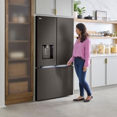 a woman standing in front of a black refrigerator