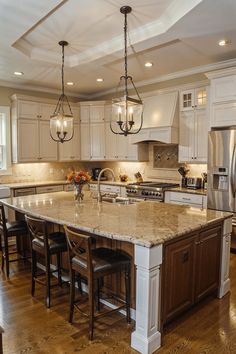 a large kitchen with an island in the middle and two lights hanging from the ceiling