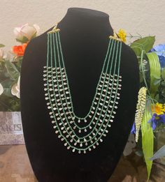 Elevate your style with this exquisite multi-layered necklace featuring emerald beads and Polki stone accents. The necklace showcases five elegant layers of green emerald beads, each adorned with sparkling Polki stones, creating a cascading effect that is both glamorous and sophisticated. This gold replica necklace is perfect for special occasions or adding a touch of elegance to any outfit. This beautiful necklace is a statement piece that will turn heads and add a touch of luxury to your jewelry collection. Don't miss out on owning this stunning accessory! Green Beaded Bridal Necklace With Round Beads, Green Kundan Necklace With Round Gemstone Beads, Elegant Green Beaded Kundan Necklace, Green Beaded Chain For Wedding, Green Kundan Necklace With Faceted Beads As Gift, Green Oval Beaded Chain Jewelry, Green Gemstone Beads For Wedding, Green Gemstone Party Beads, Elegant Green Kundan Necklace With Round Beads