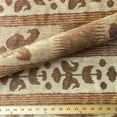 a ruler is next to a rug with brown and white designs on it, as well as a measuring tape