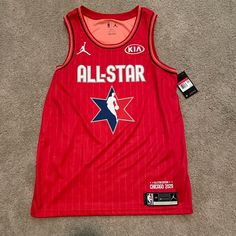 a red basketball jersey with the word all - star on it is laying on the floor