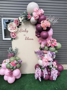 balloons and flowers decorate the backdrop for a baby to bloom party in pink, white, and green