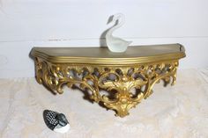 a swan figurine sitting on top of a gold shelf next to a sea shell