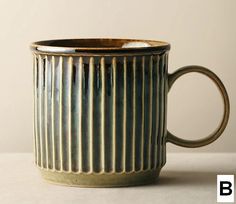 a coffee cup sitting on top of a table next to a white wall and floor